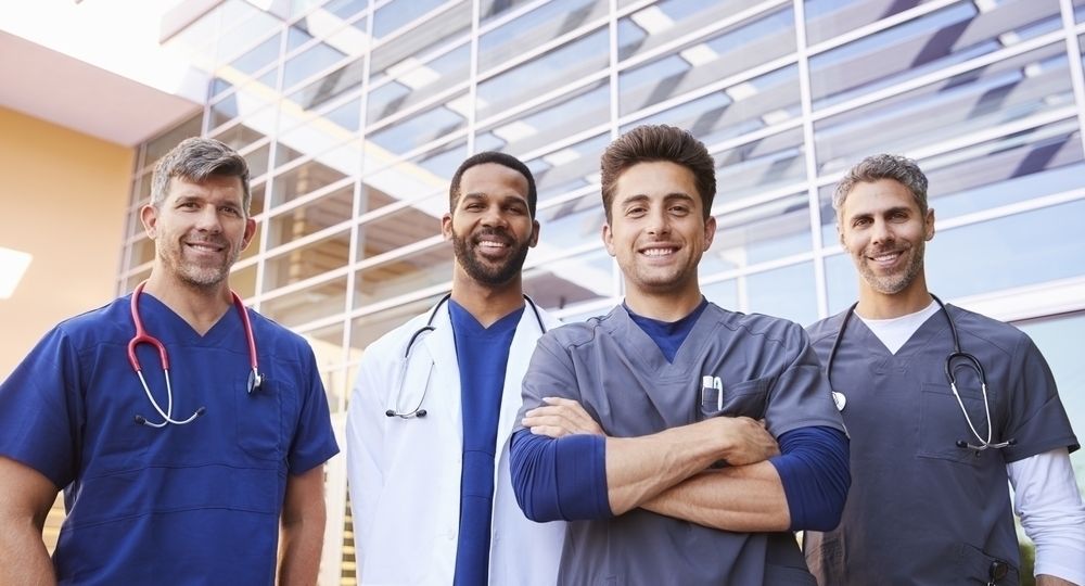 Male healthcare colleagues standing outdoors, low angle