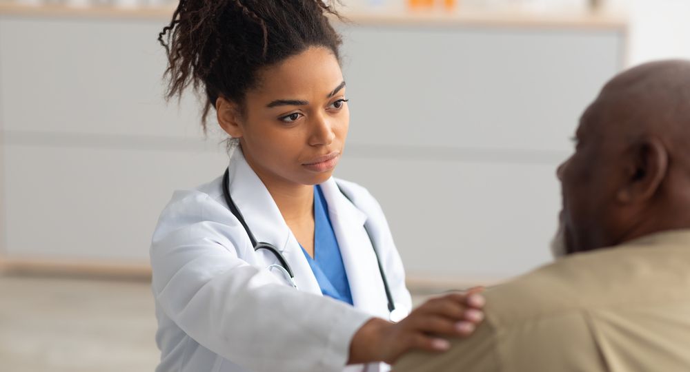 Close up of black female doctor tapping patting patient's shoulder