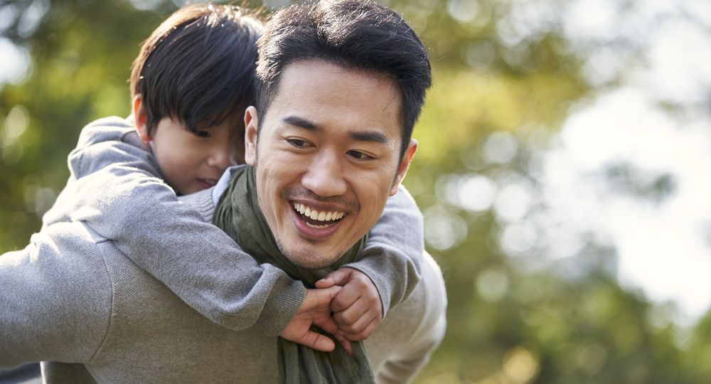 asian father and son having fun outdoors in park