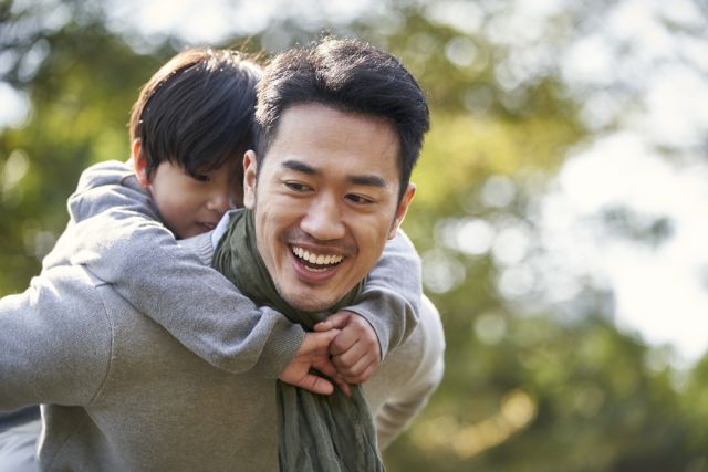 asian father and son having fun outdoors in park