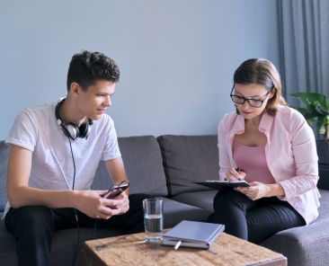 Teenage boy at meeting with female professional doctor psychologist. Adolescent counseling help, school psychologist, child social worker, adolescent problems