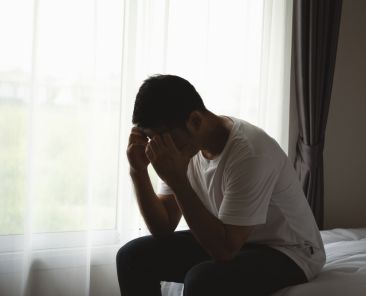 Silhouette depressed man sadly sitting on the bed in the bedroom. Sad asian men suffering depression insomnia awake and sit alone on the bed in bedroom. Depression health people concept.