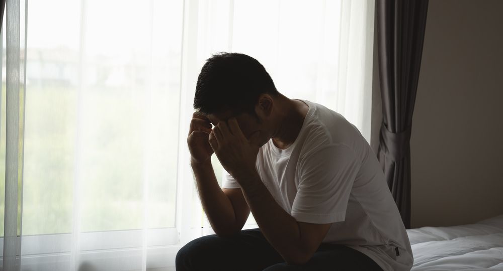 Silhouette depressed man sadly sitting on the bed in the bedroom