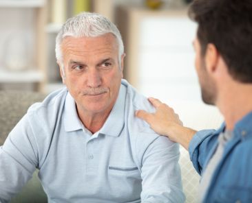 adult son sitting on sofa and talking to father