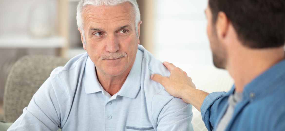 adult son sitting on sofa and talking to father