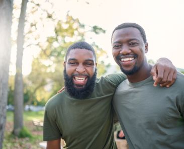 Black men, friends and happy face portrait of volunteer people outdoor at a nature park in summer. People together for community service in a green ngo tshirt for recycling and a clean enviroment.