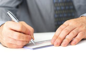 Closeup of man's hands writing a cheque